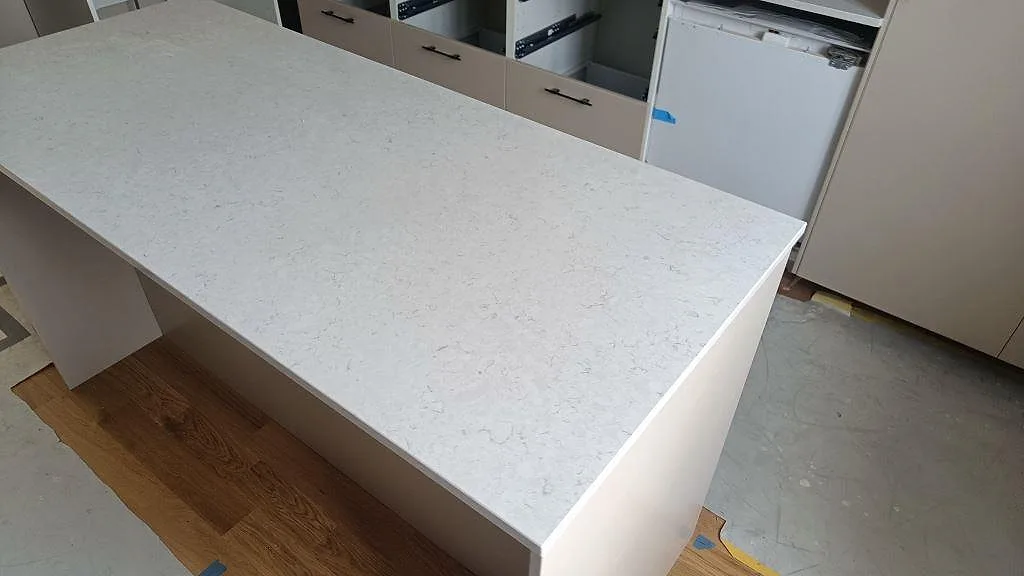 Stor arbetsyta i vit Silestone Snowy Ibiza, polerad kvartskomposit, monterad på köksö i Lund.