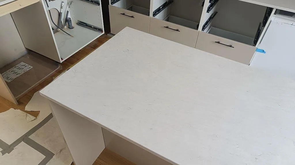 Ovanvy av polerad Silestone Snowy Ibiza på köksö med diskret grå ådring och öppna köksstommar i Lund.