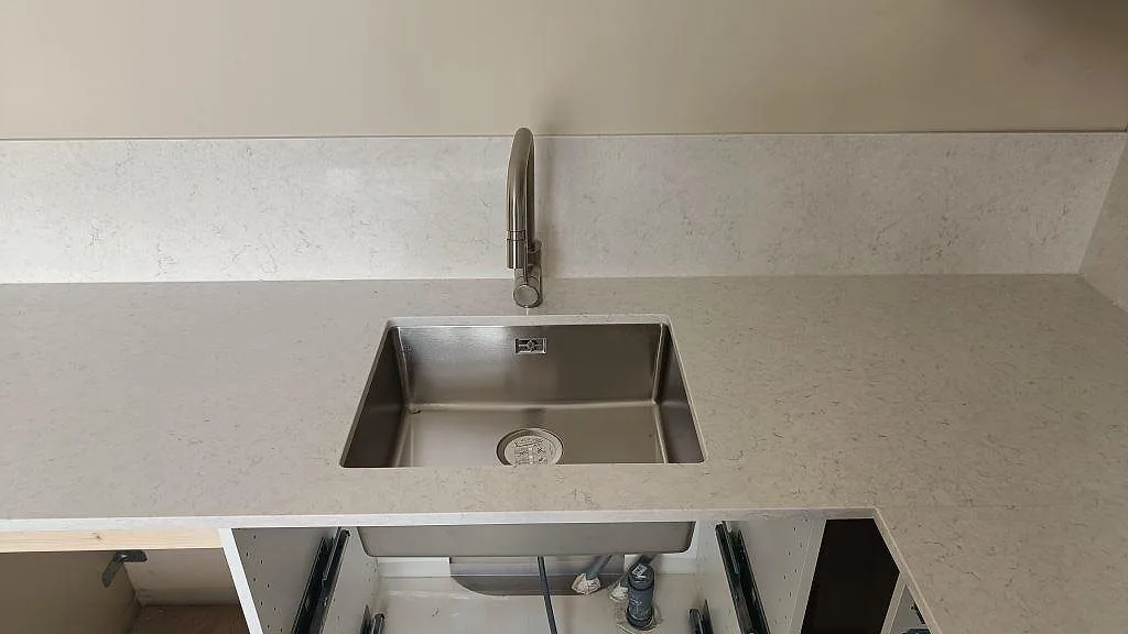 Underlimmad rostfri diskho i en köksbänkskiva av polerad Silestone Snowy Ibiza i ett kök i Lund.