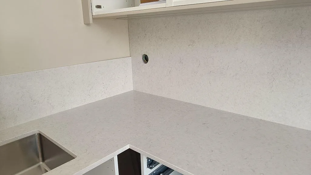 Hörndel med polerad Silestone Snowy Ibiza som bänkskiva och stänkskydd bakom diskzonen i Lund.