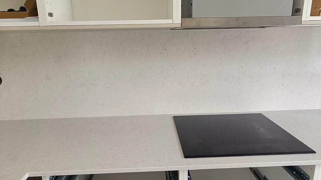 Induktionshäll infälld i polerad Silestone Snowy Ibiza med matchande stänkskydd i ett kök i Lund.