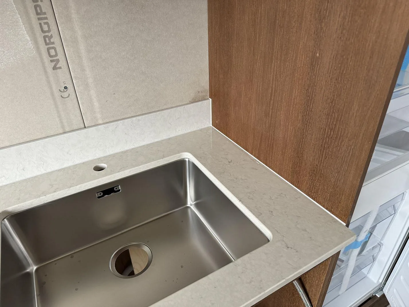 Hörn vid diskhon med polerad Silestone Snowy Ibiza komposit, rostfri diskho och 12 mm stänkkant i Lund.