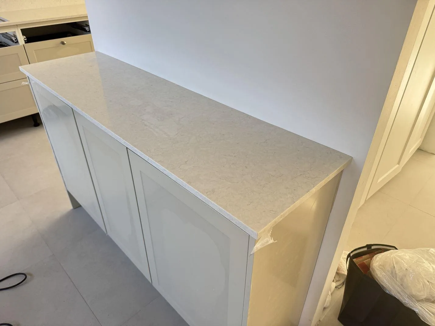 Polerad Silestone Snowy Ibiza på separat bänkdel med ljus ådring och vita köksluckor i Lund.