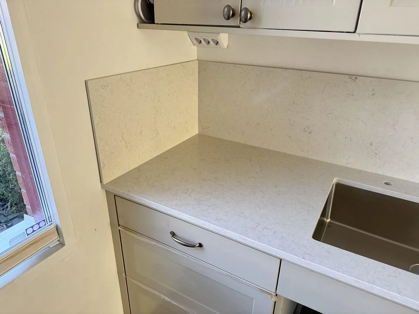 Polerad Silestone Snowy Ibiza vid kökets diskzon med matchande stänkskydd och vit skåpinredning i Lund.