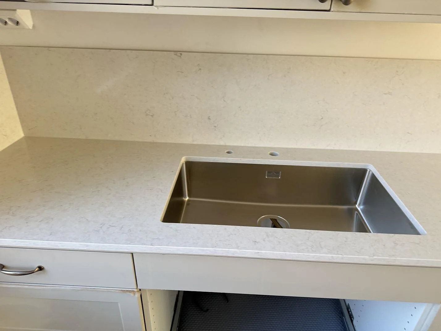 Detalj av polerad Silestone Snowy Ibiza runt diskzonen med lågt stänkskydd i samma sten i Lund.