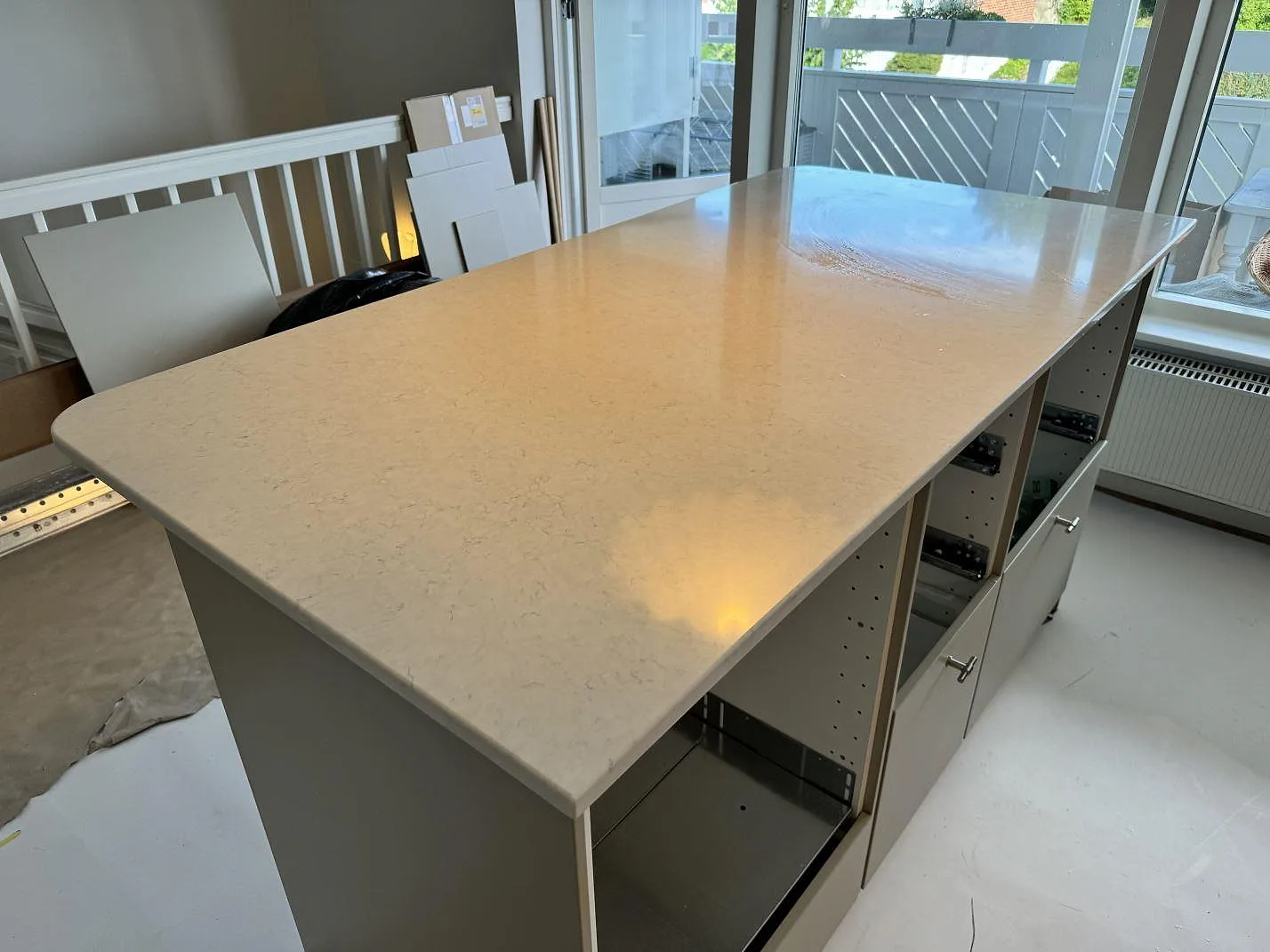 Närbild av köksö i polerad Silestone Snowy Ibiza, vit kompositsten, med mjuk ådring i ett kök i Lyckeby.