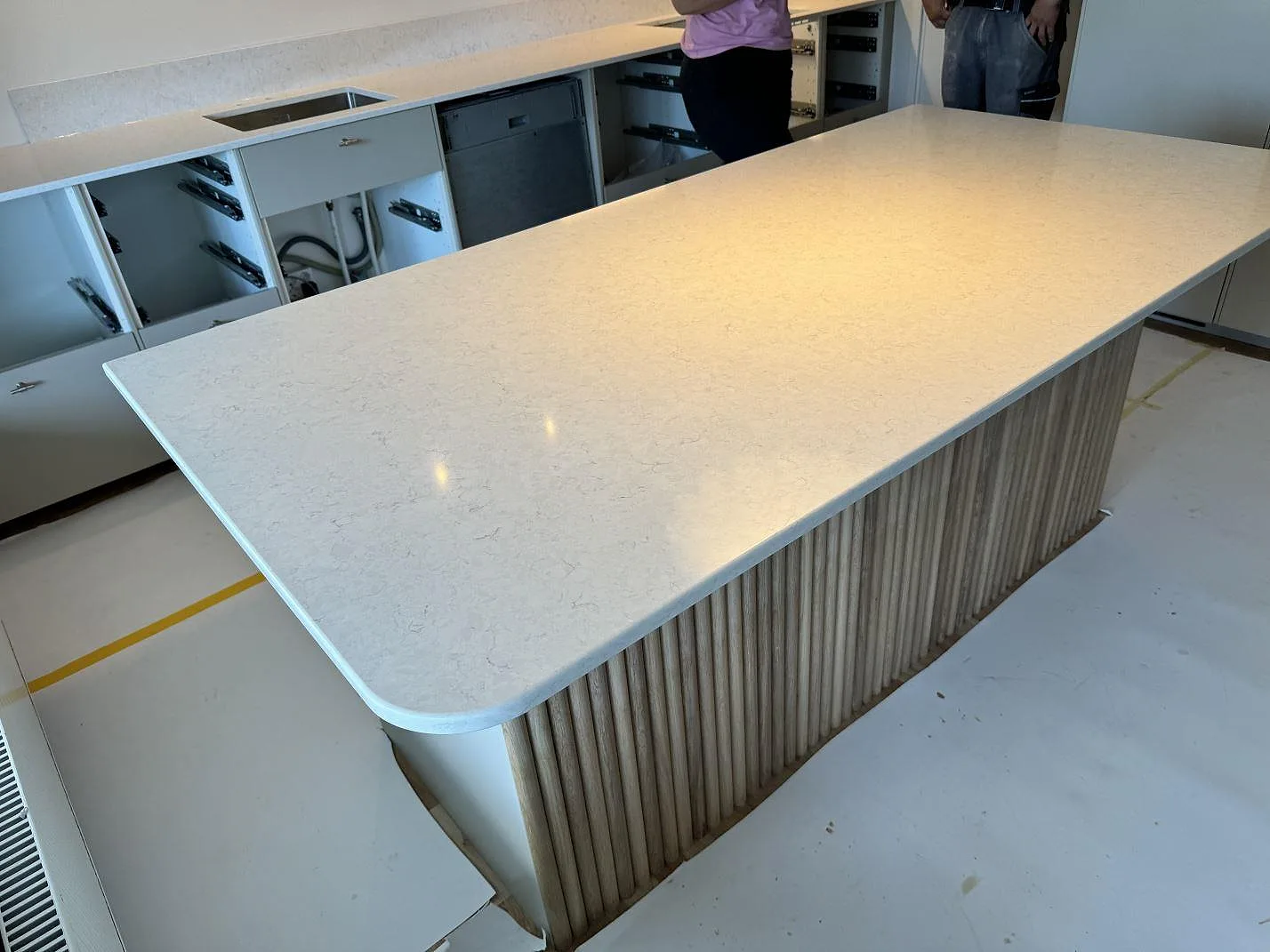 Köksö med rundat hörn och polerad Silestone Snowy Ibiza framför väggbänk med stänkskydd i Lyckeby.