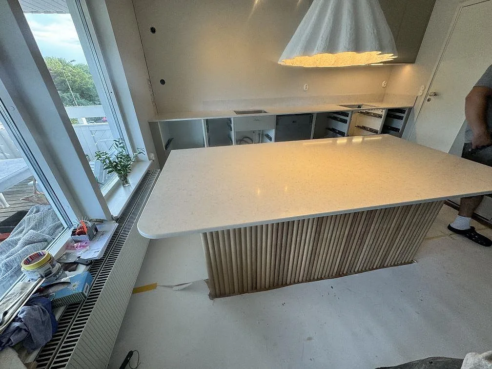 Översiktsbild av kök i Lyckeby med polerad Silestone Snowy Ibiza på köksö, väggbänk och lågt stänkskydd.