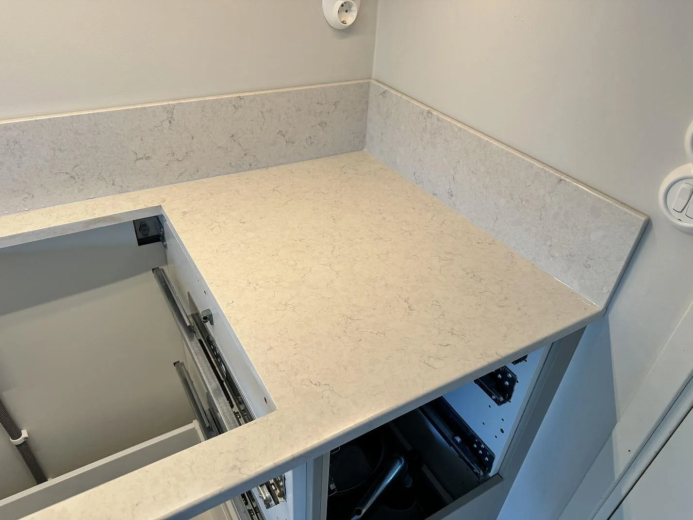 Hörndel av köksbänkskiva i polerad Silestone Snowy Ibiza med uppvikt stänkskydd i Lyckeby.