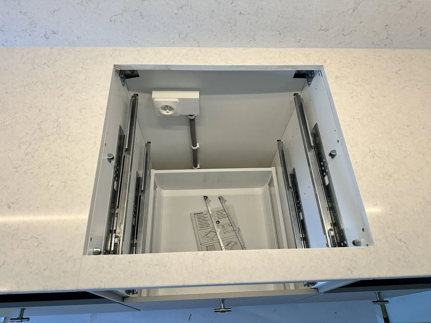 Detalj av polerad Silestone Snowy Ibiza med öppning i bänkskivan och lågt stänkskydd i köket i Lyckeby.