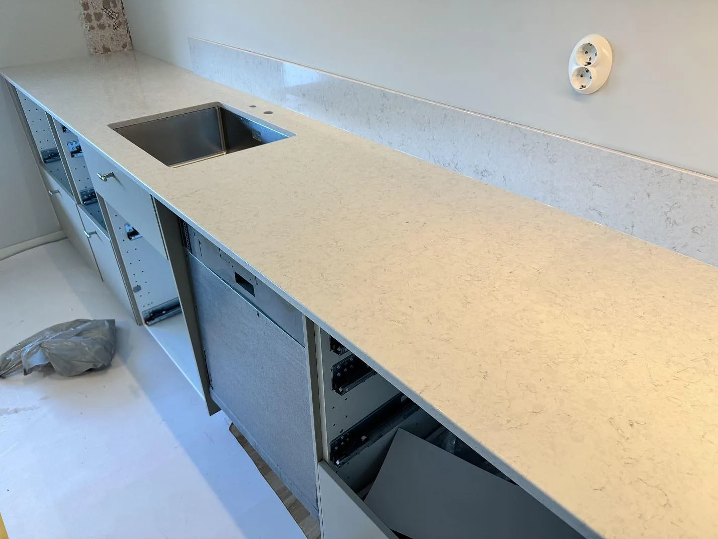 Lång köksbänkskiva i polerad Silestone Snowy Ibiza med stänkskydd och diskhozon i köket i Lyckeby.