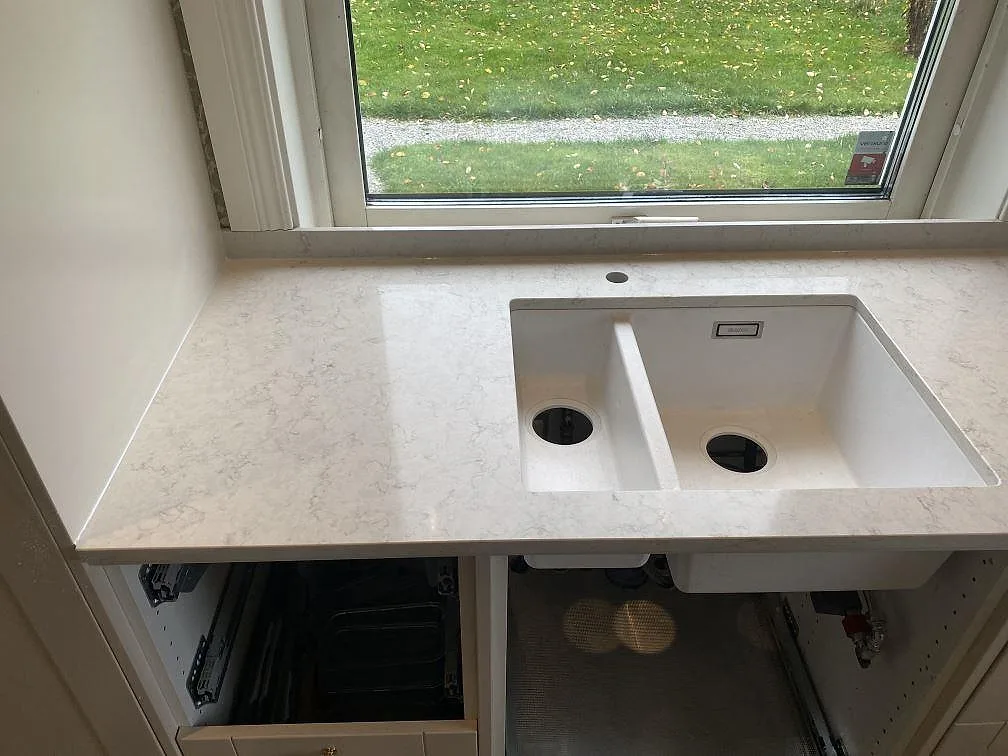 Polerad Silestone Snowy Ibiza som köksbänkskiva vid fönster med vit ho och ljus ådring i Målsryd.