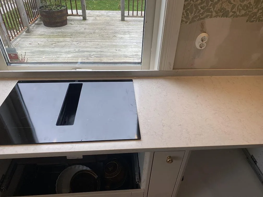 Detalj av polerad Silestone Snowy Ibiza runt vit ho med fönster och ljus köksbänk i Målsryd.