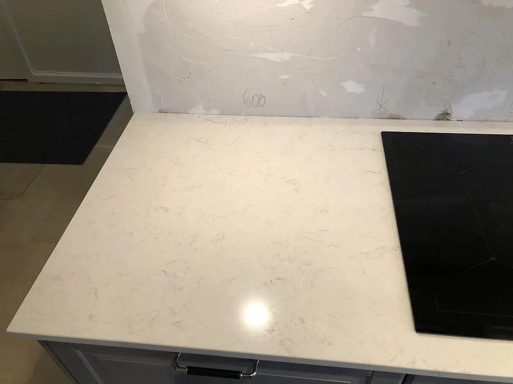 Köksbänkskiva i Silestone Snowy Ibiza, polerad komposit, med svart induktionshäll inhuggen i bänken i ett Malmökök.