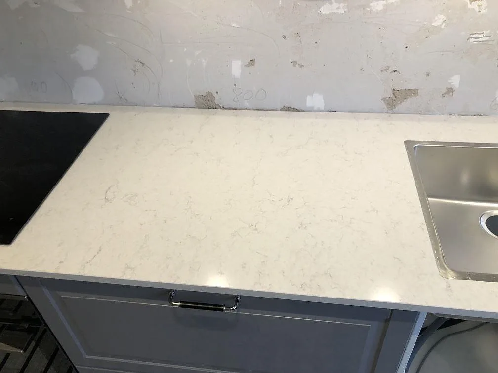 Vit Silestone Snowy Ibiza köksbänkskiva med infälld rostfri diskho och svart induktionshäll i ett kök i Malmö under installation.