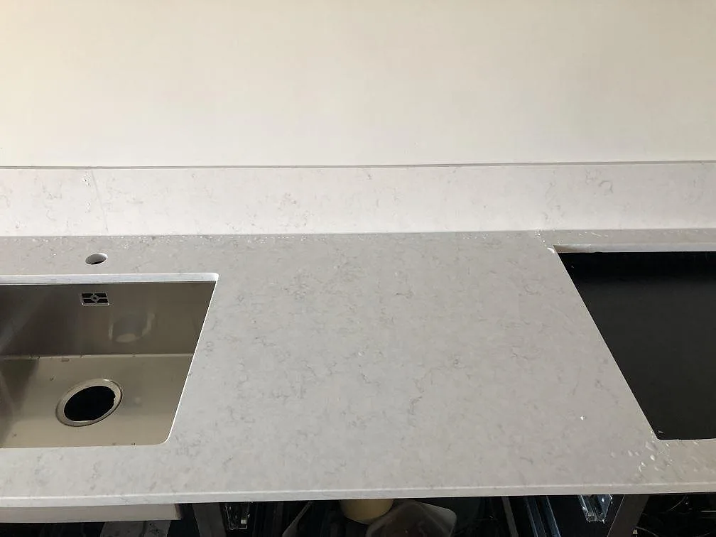 Underlimmad rostfri diskho i en vit Silestone Snowy Ibiza-bänkskiva med borrat blandarhål i ett kök i Malmö.