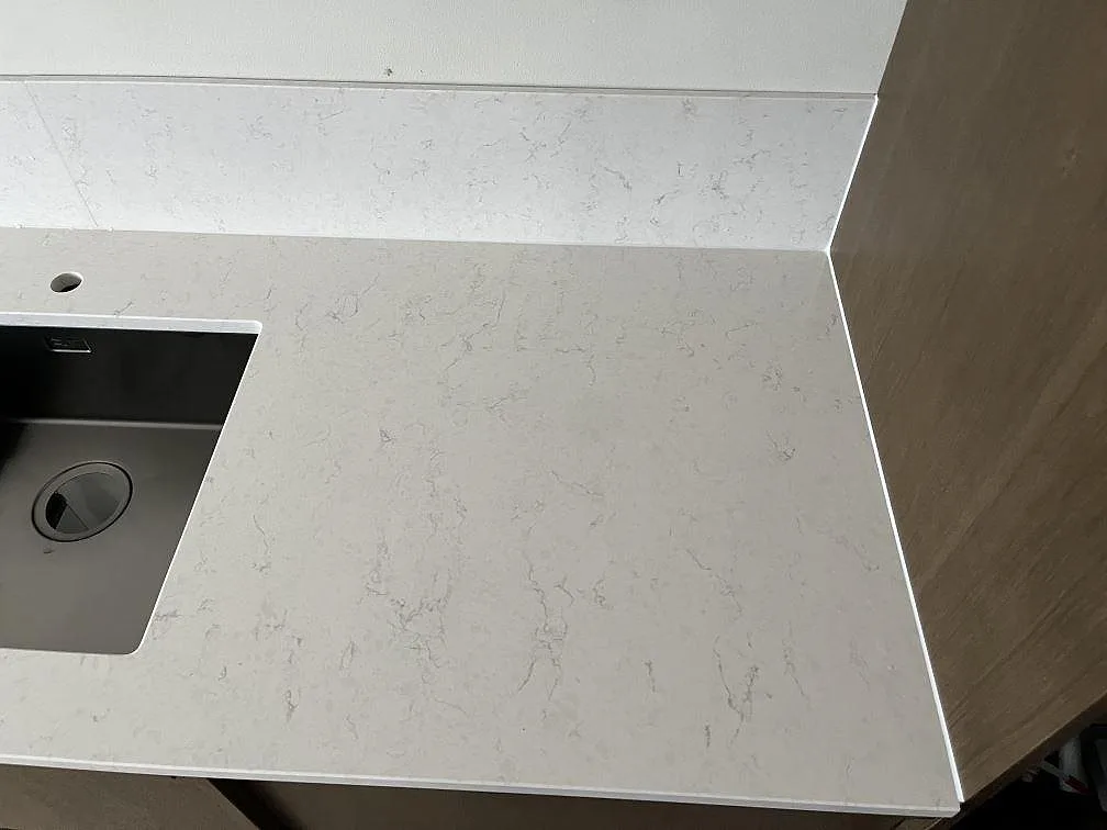 Underlimmad diskho och borrat blandarhål i vit Silestone Snowy Ibiza-bänkskiva med uppvikt stänkkant i ett kök i Malmö.