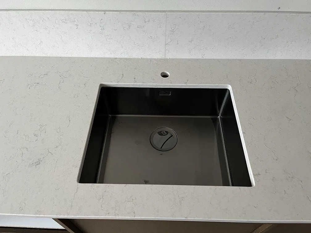 Fyrkantig underlimmad diskho i mörkt stål i en vit Silestone Snowy Ibiza-bänkskiva i ett kök i Malmö.