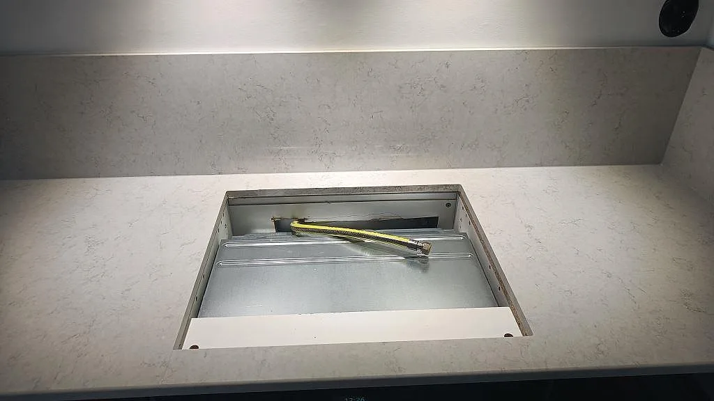 Polerad bänkskiva i Silestone Snowy Ibiza med urtag för häll under montering i ett kök i Malmö.