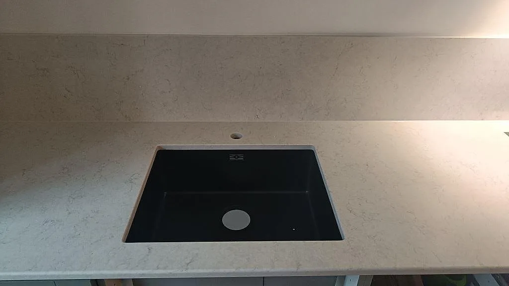 Närbild på svart underlimmad kompositdiskho i en polerad bänkskiva i Silestone Snowy Ibiza i ett kök i Malmö.