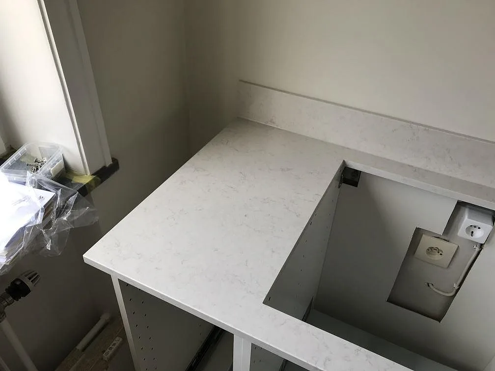 Hörn av en köksbänkskiva i vit Silestone Snowy Ibiza mot fönster, fotad under montering med öppna köksstommar i Malmö.