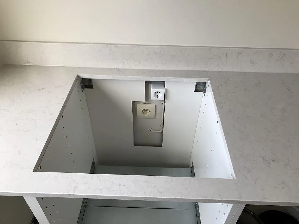 Topvy av en köksbänkskiva i Silestone Snowy Ibiza med fyrkantig hällurtagning och eluttag i ett kök under montering i Malmö.