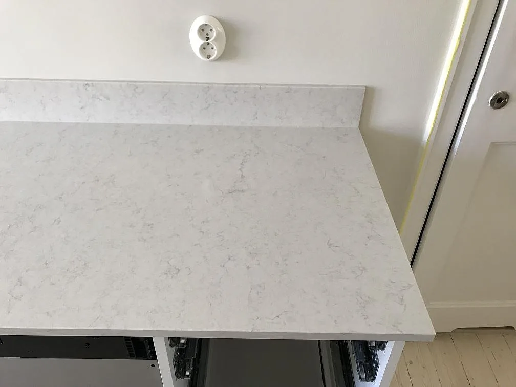 Köksbänkskiva i Silestone Snowy Ibiza med uppvikt stänkkant och eluttag, fotad under montering i ett kök i Malmö.