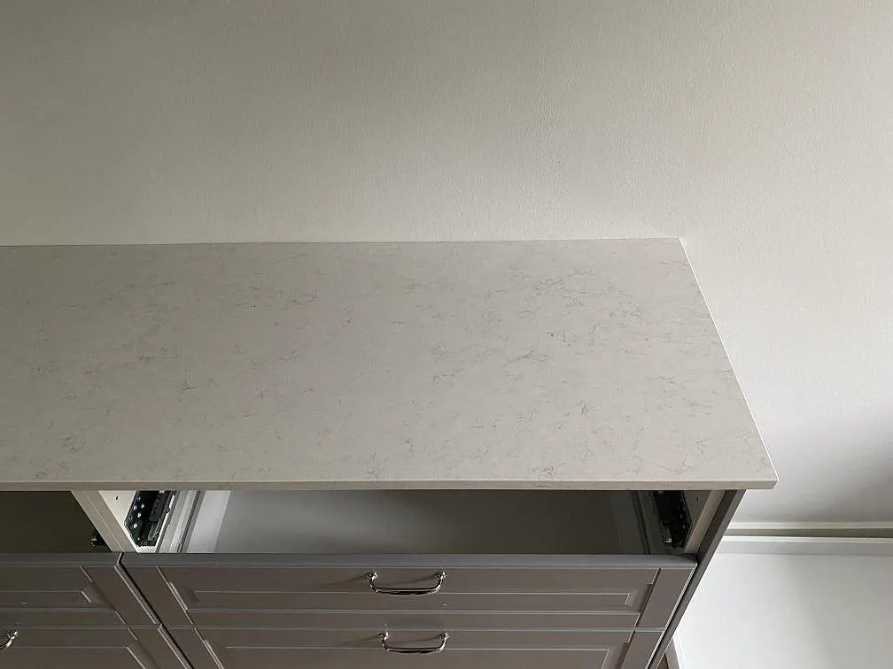 Köksbänkskiva i polerad Silestone Snowy Ibiza mot vit vägg i ett kök under montering i Malmö.
