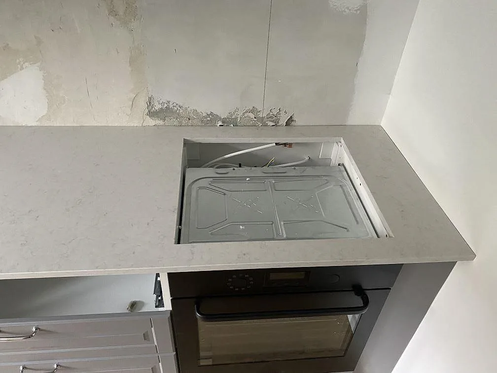 Bänkskiva i Silestone Snowy Ibiza med urtag för häll ovanför inbyggnadsugn i ett kök i Malmö.