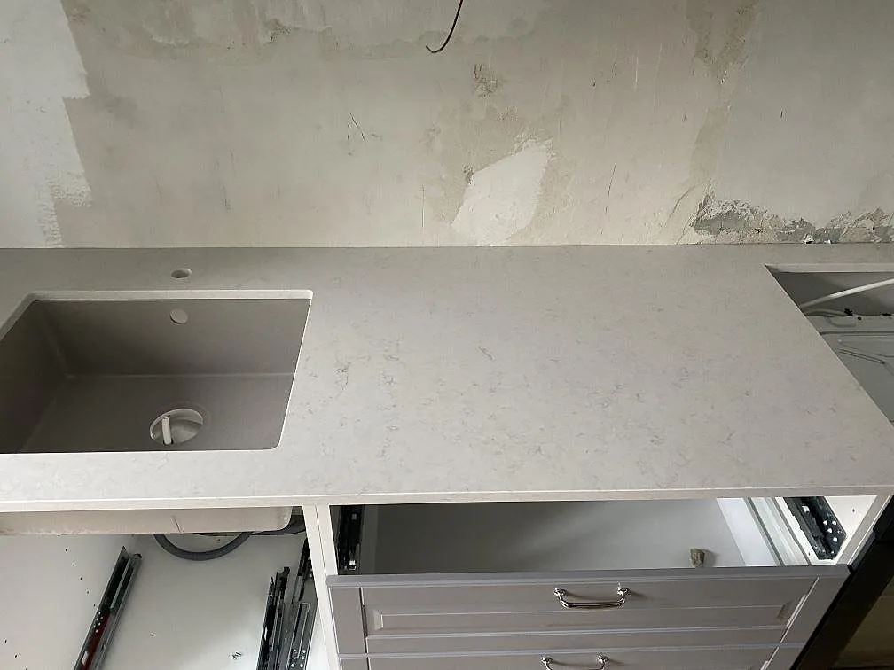 Polerad bänkskiva i Silestone Snowy Ibiza med diskhourtag och blandarhål, sedd ovanifrån i ett Malmökök under installation.