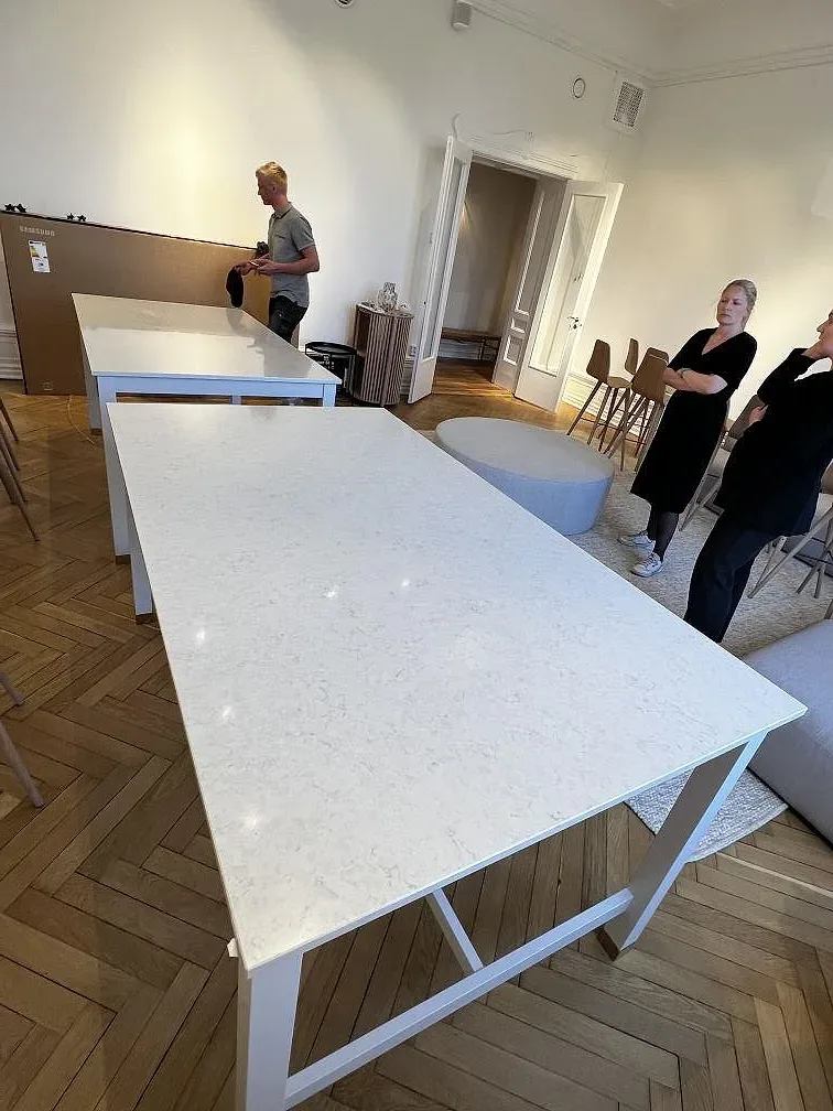 Polerad bordsskiva i Silestone Snowy Ibiza på vitt bordsunderrede i ett rum med stolar och fiskbensparkett i Malmö.