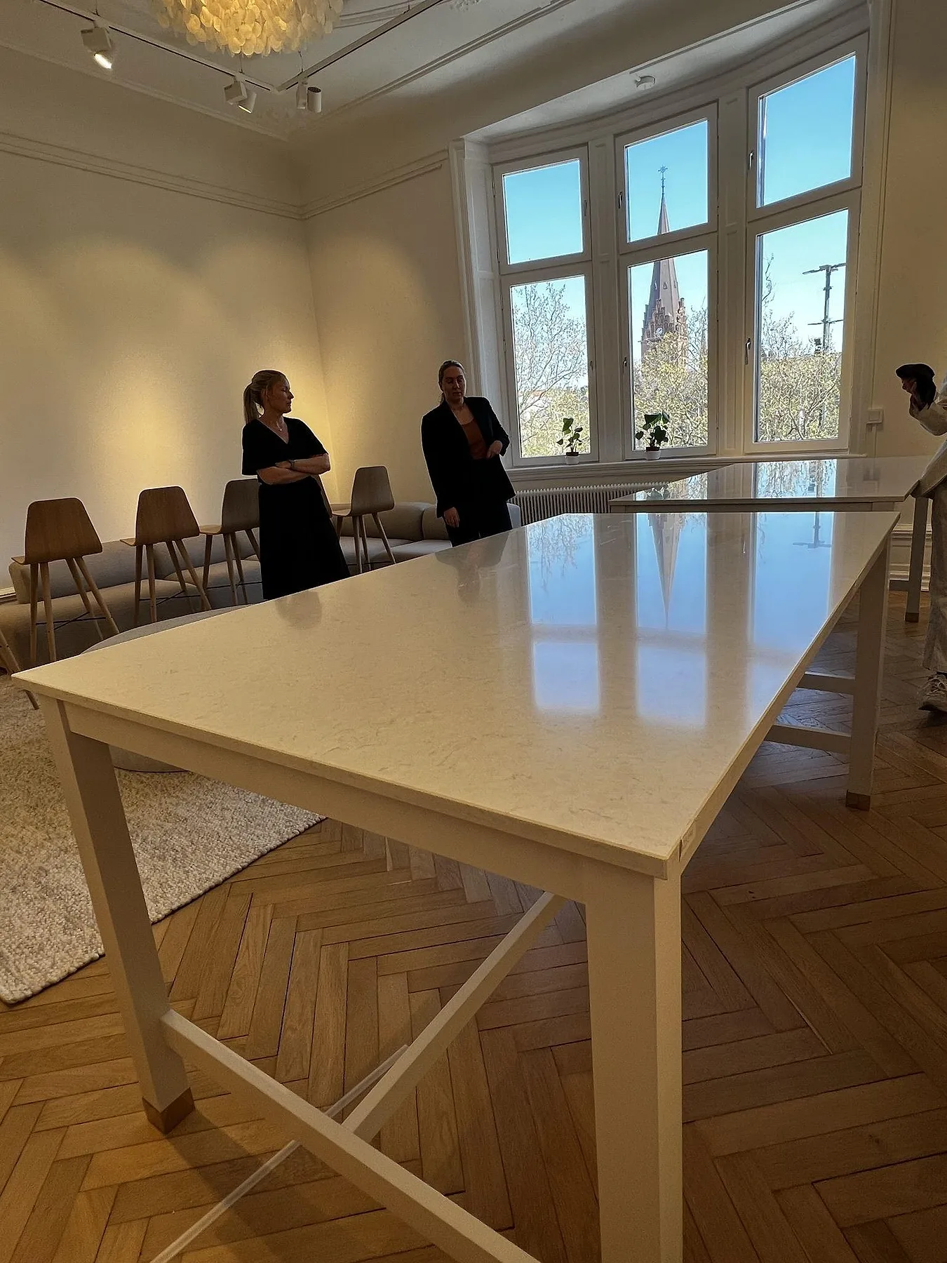 Stor bordsskiva i vit Silestone Snowy Ibiza, polerad, på vita ben i ett rum med fiskbensparkett och stora fönster i Malmö.