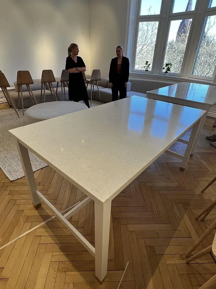 Bordsskiva i ljus Silestone Snowy Ibiza, polerad, med reflektioner från stora fönster i ett möblerat rum i Malmö.