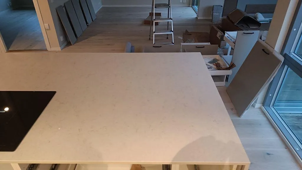 Polerad Silestone Snowy Ibiza komposit på köksö med ljus ådring och svart häll i ett kök i malmö.