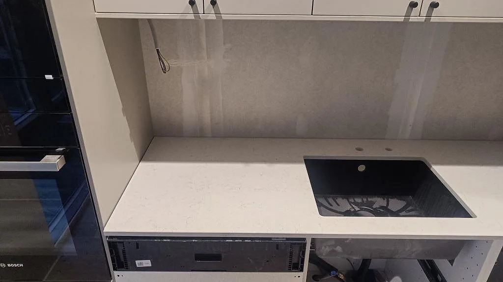 Diskbänksdel med polerad Silestone Snowy Ibiza komposit, mörk diskho och stenskiva bakom arbetsytan i malmö.