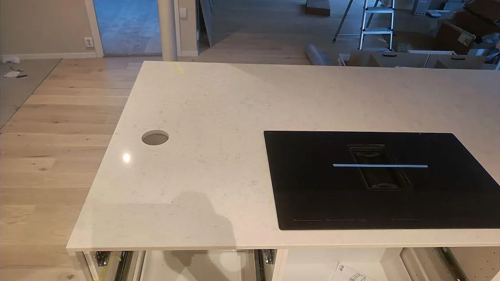 Polerad perimeterbänk i Silestone Snowy Ibiza med induktionshäll och uttag för blandare i ett kök i Malmö.