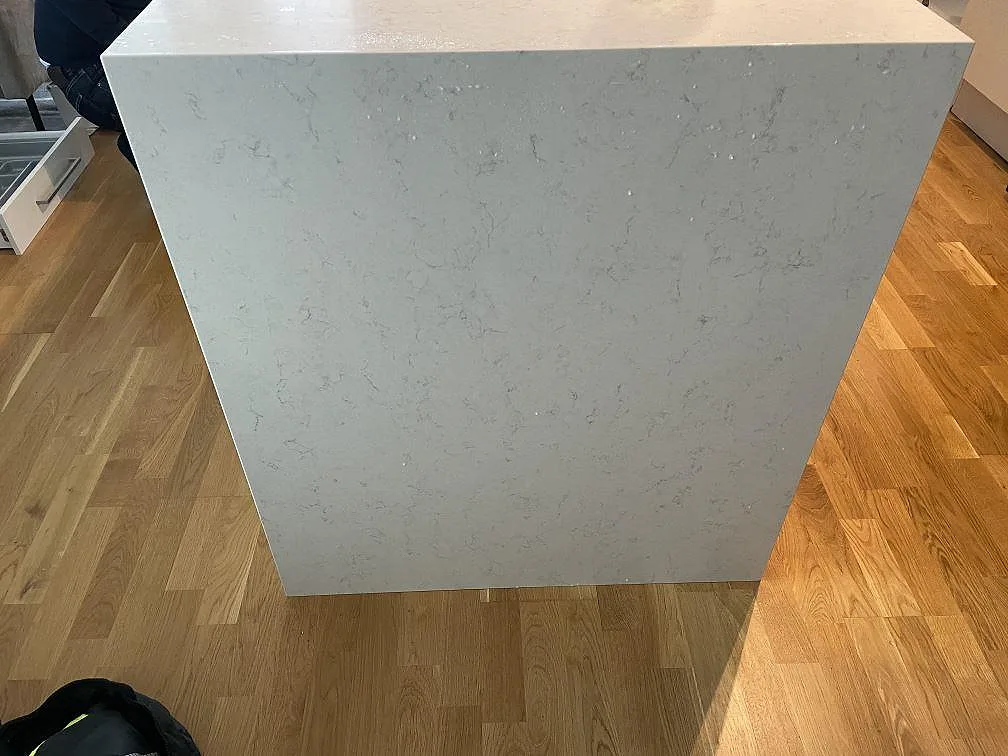 Köksö med waterfall-kant i vit Silestone Snowy Ibiza mot ekgolv i ett kök i Malmö.