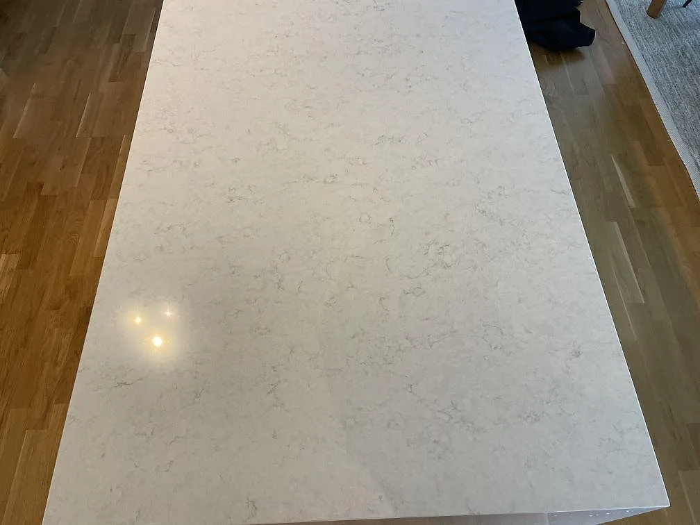 Stor köksö i polerad Silestone Snowy Ibiza sedd ovanifrån med mjuk grå ådring i ett kök i Malmö.