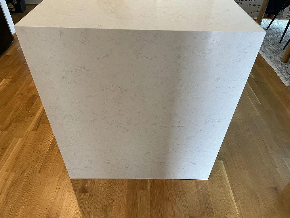 Köksö i vit Silestone Snowy Ibiza, polerad, med waterfall-kant ner till ekgolvet i ett kök i Malmö.