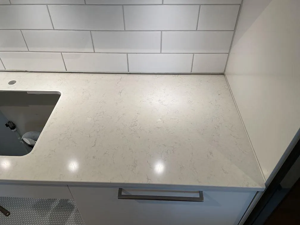 Köksbänkskiva i vit Silestone Snowy Ibiza, polerad, mot vitt metrokakel med urtag för underlimmad diskho i ett kök i Malmö.