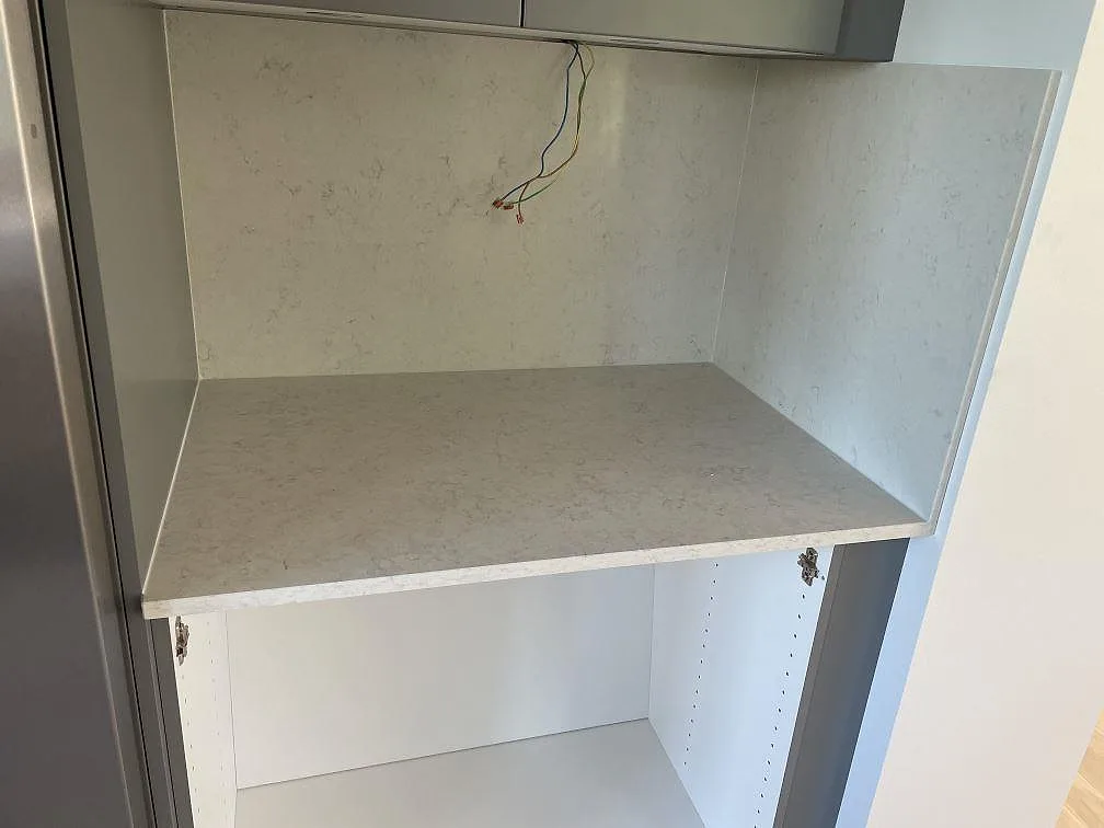 Sidoyta med bänkskiva och stänkskydd i polerad Silestone Snowy Ibiza komposit under grå överskåp i Malmö.