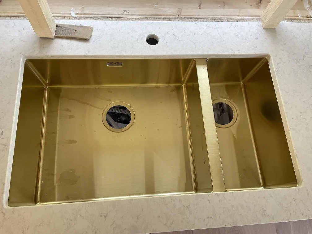 Mässingsfärgad underlimmad dubbelho i polerad Silestone Snowy Ibiza komposit med blandarhål i Malmö.
