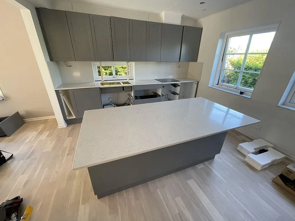 Stor köksö och köksbänkskivor i polerad Silestone Snowy Ibiza komposit med grå köksstommar i Malmö.