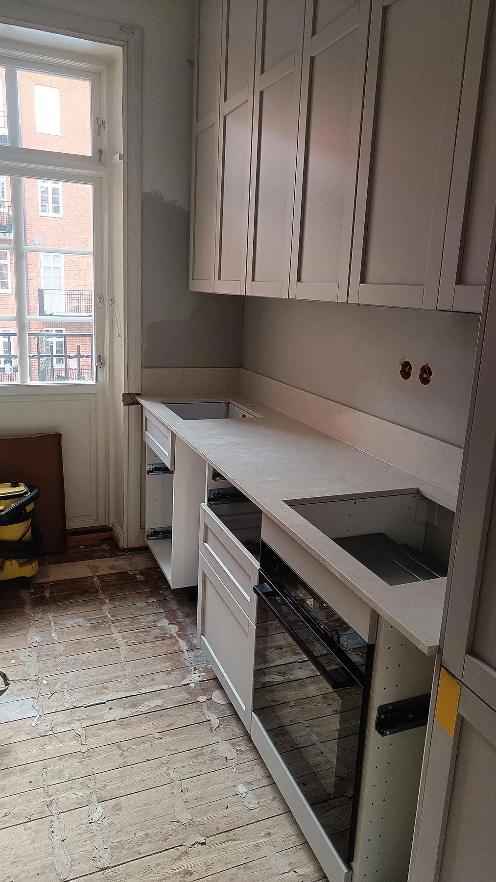 L-formad köksbänkskiva i polerad Silestone Snowy Ibiza med hällöppning, stänkskydd och vit köksinredning under montering i Malmö.