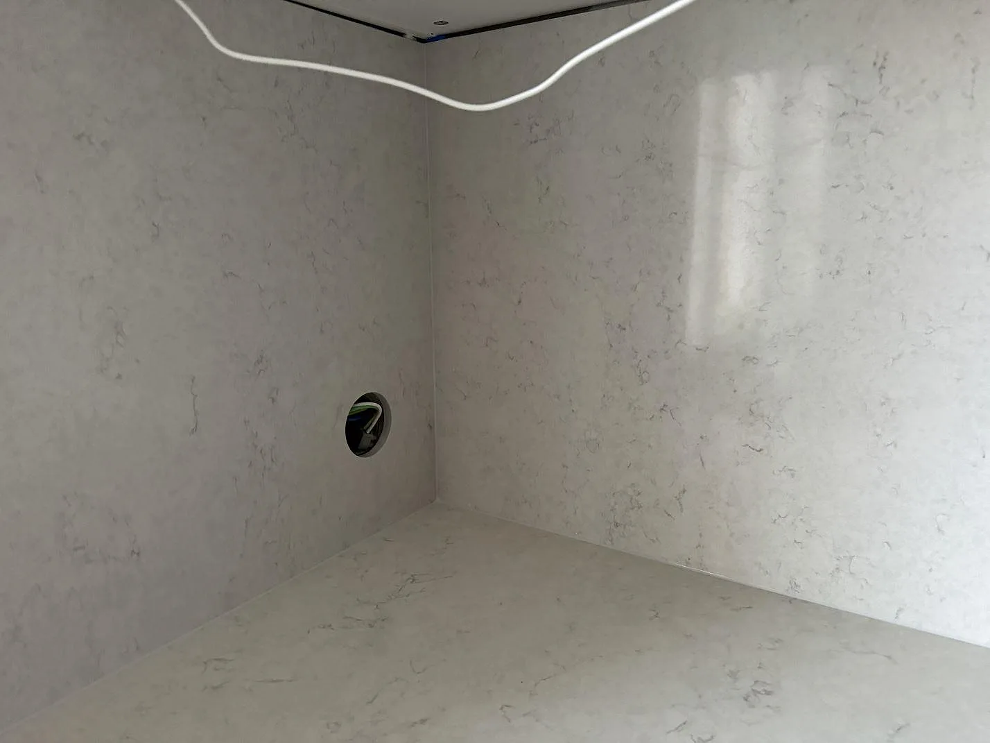 Närbild på ljus Silestone Snowy Ibiza som polerad bänkskiva och väggskiva i ett kök i Malmö.