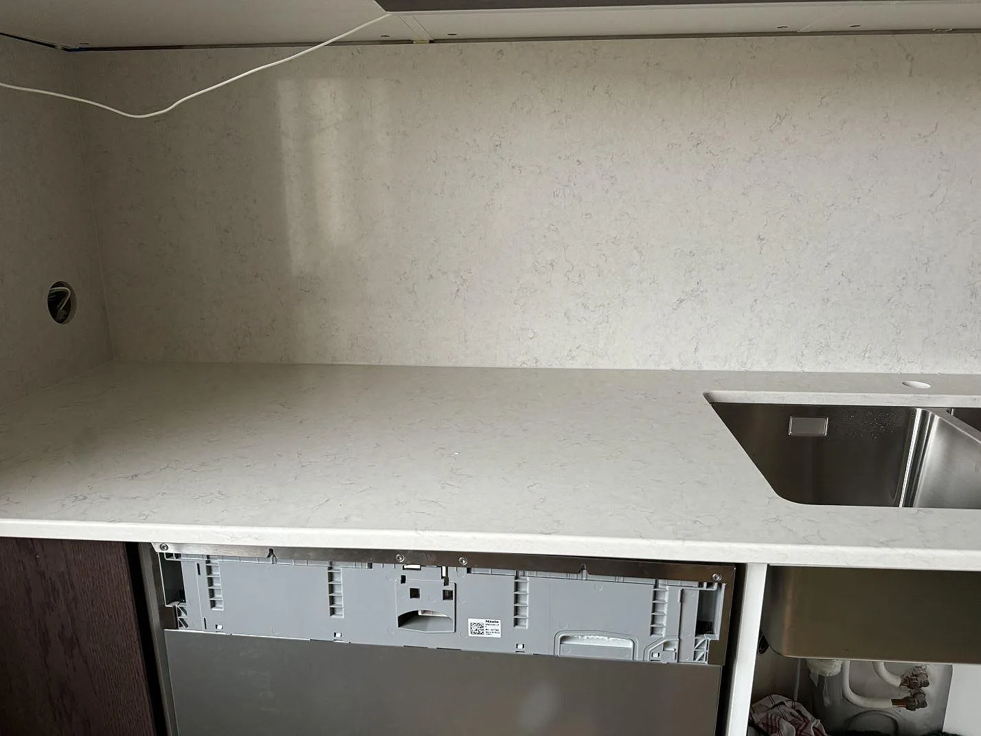 Lång köksbänkskiva i polerad Silestone Snowy Ibiza med matchande stänkskydd och rostfri diskho i ett kök i Malmö.