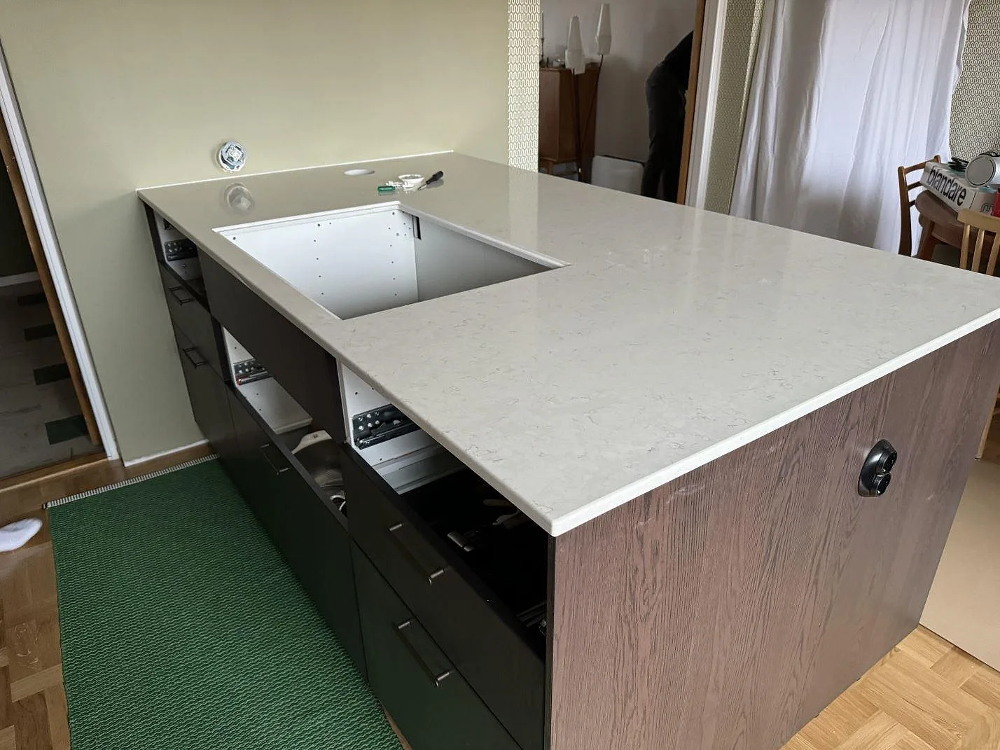 Polerad köksö och köksbänkskiva i Silestone Snowy Ibiza med ljus kvartskomposit och mörk träinredning i Malmö.