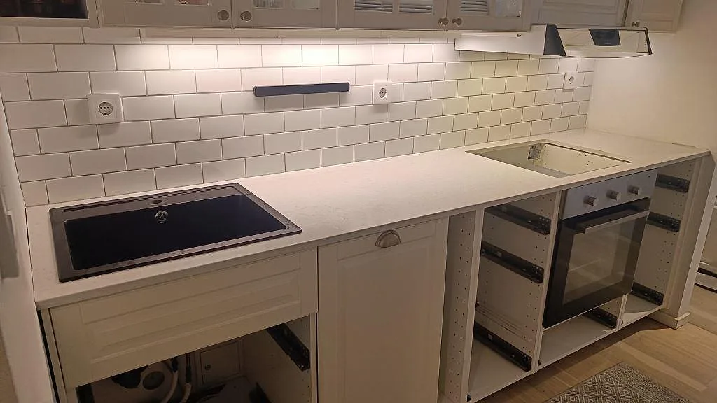 Köksbänkskiva i vit Silestone Snowy Ibiza, polerad, med mörk diskho och hällöppning i ett kök i Malmö.