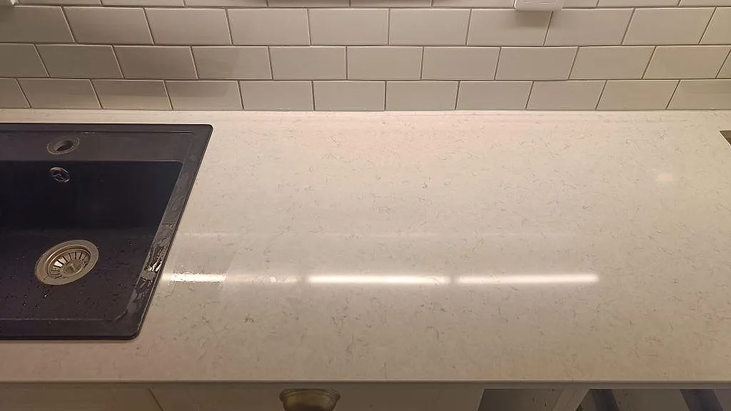 Polerad vit kompositbänkskiva i Silestone Snowy Ibiza med diskho och ljus ådring i Malmö-kök.
