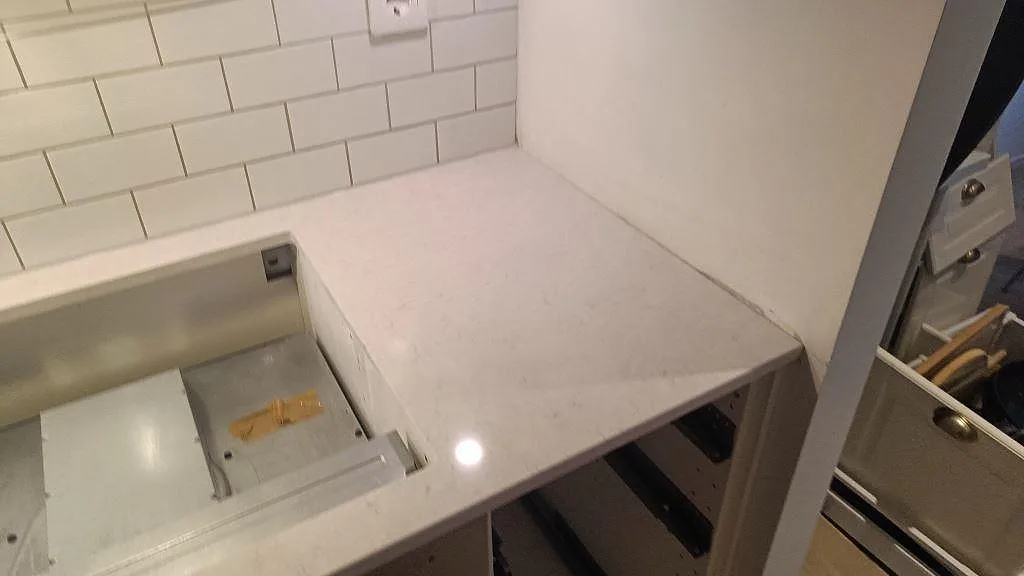 Hörnbit av polerad Silestone Snowy Ibiza vid hällöppningen under montering i ett kök i Malmö.